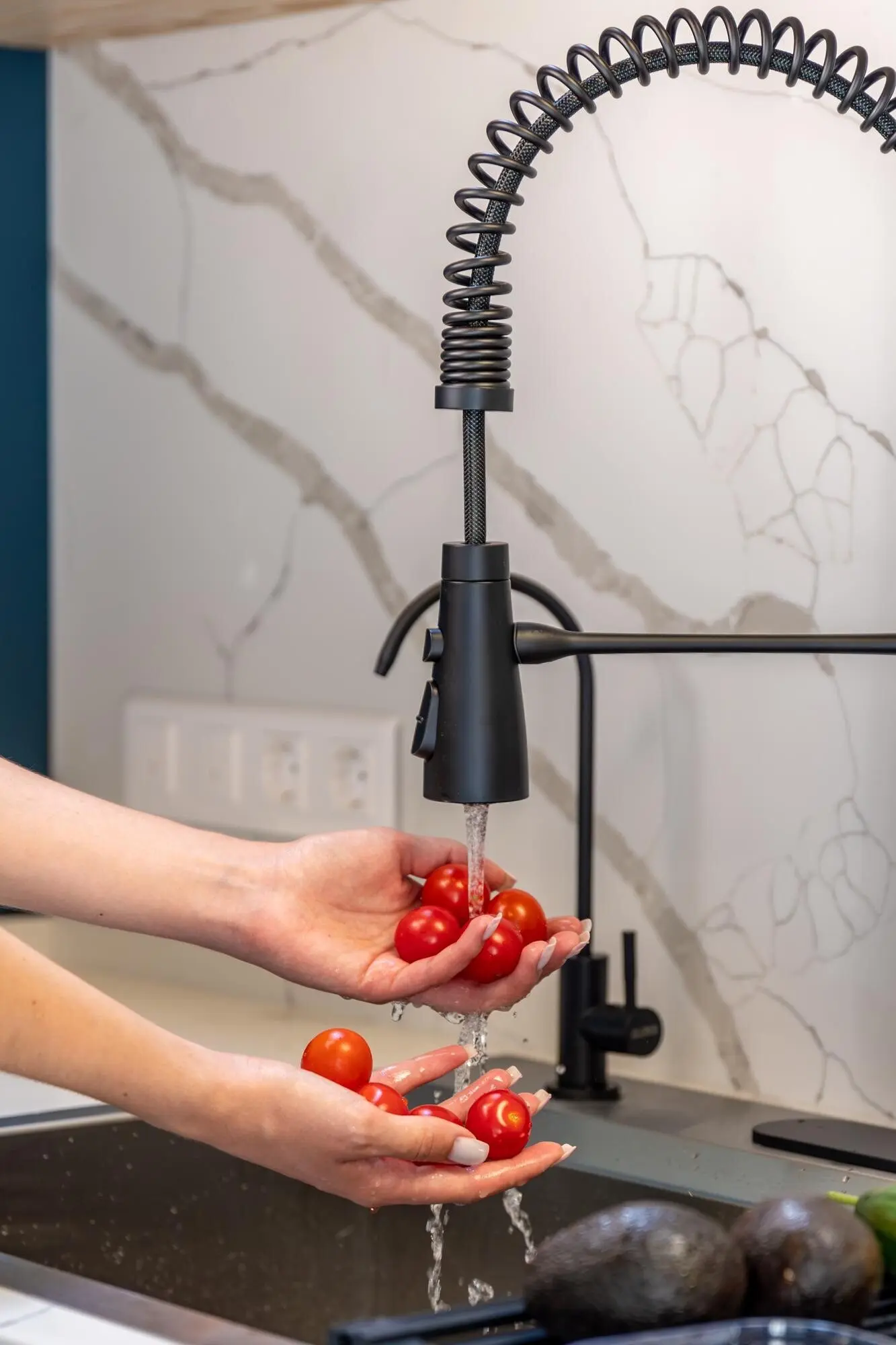 Женские руки моют помидоры черри под краном — чистая подготовка.